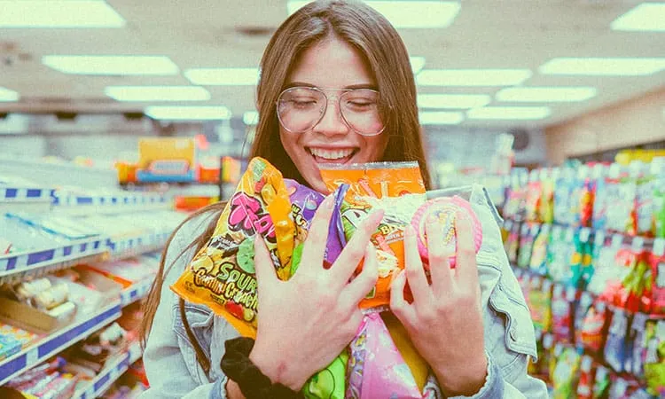 a girl holding packs of sweets in a store