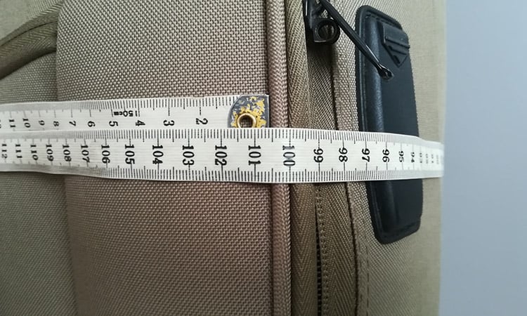 measuring luggage with a measure tape