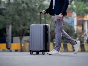 a man walking with a gray spinner suitcase