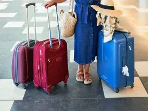 A woman standing in airport with hardside and softside luggage