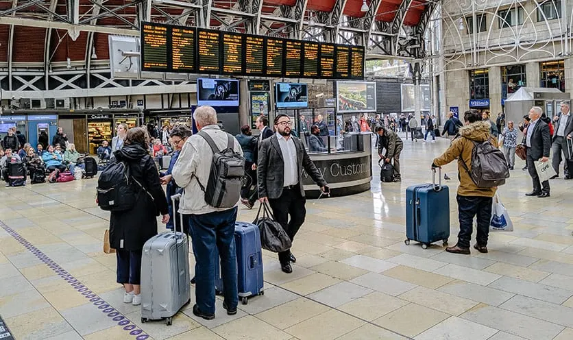 People waiting in airport with suticases, backpacks, and duffle bags