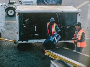 Baggage handlers loading checked luggage on a plane