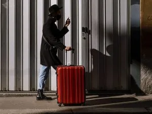 A woman walking with a bright red hardside suitcase