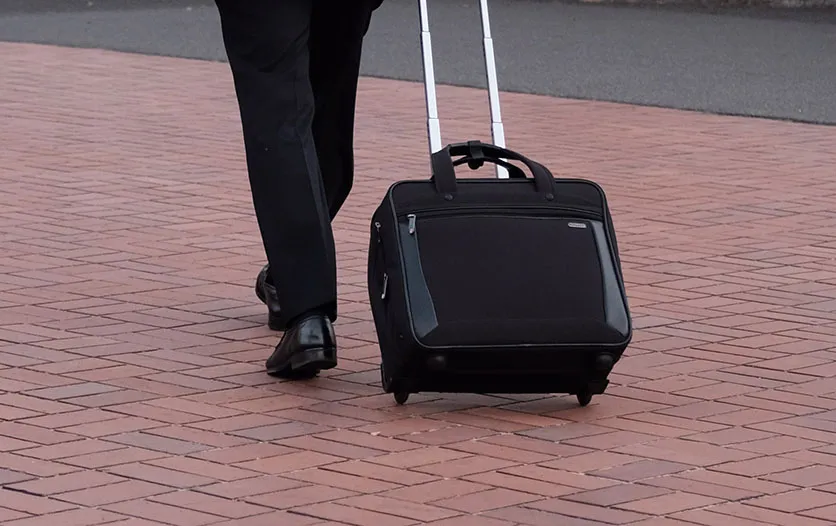 A bysiness man walking with a casual black suitcase