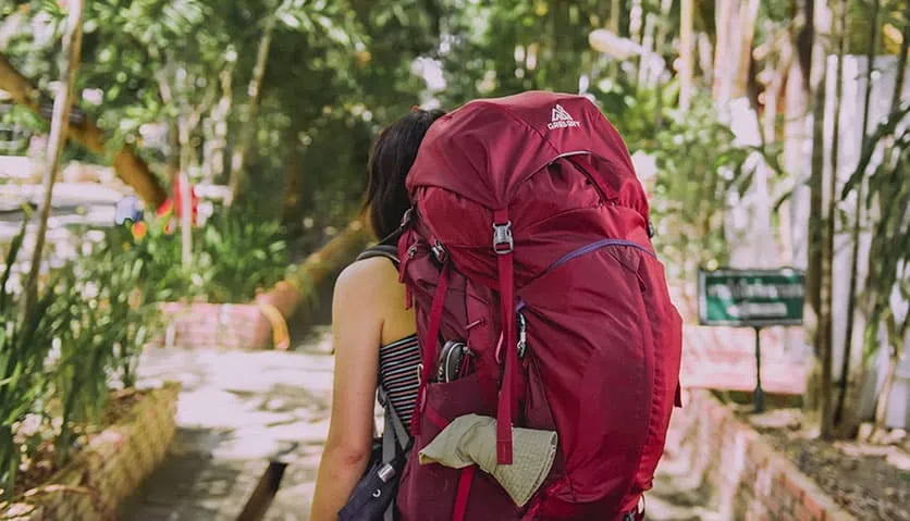 A girl using a large red backpack in southern Europe