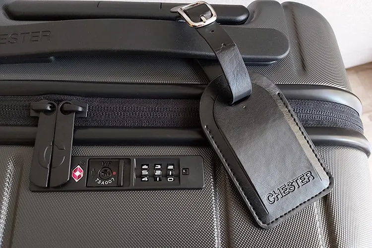 a black leather luggage tag attached to a suitcase's top handle