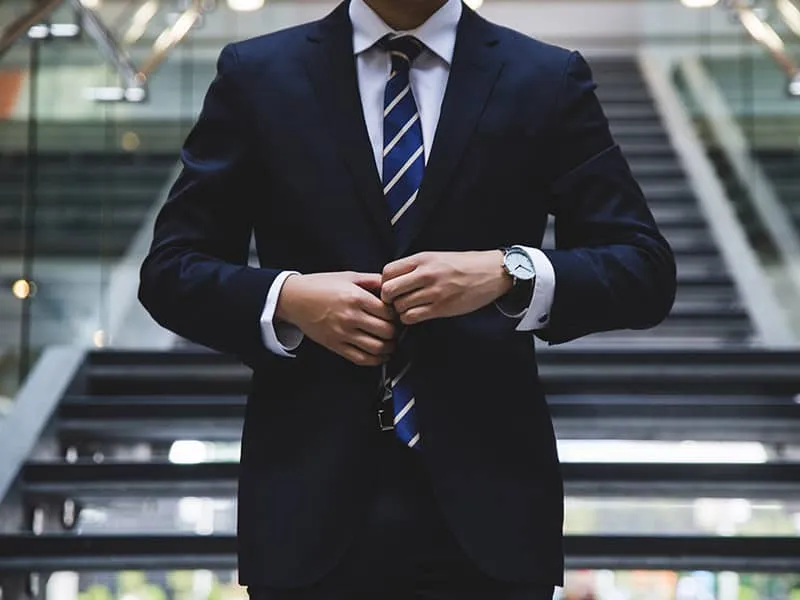 A man in a dark blue suit standing near stairs