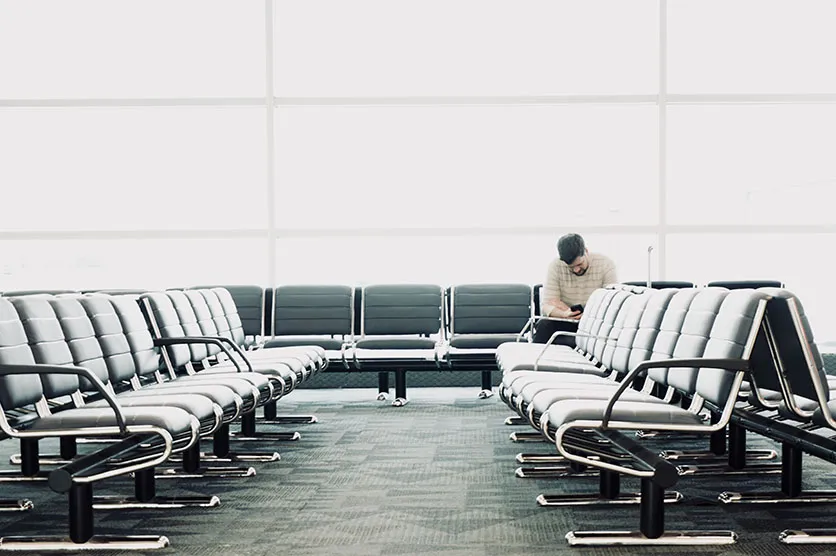 An single man sitting inside an airport near the gate