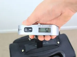 Measuring the weight of the Maxlite Travelpro 5 fabric suitcase with a luggage scale