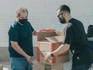 Two men carrying a single cardboard box