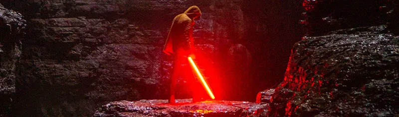 man using a red lightsaber replica in a dark cave