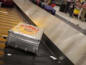A single checked suitcase without a passenger on a luggage converyor belt
