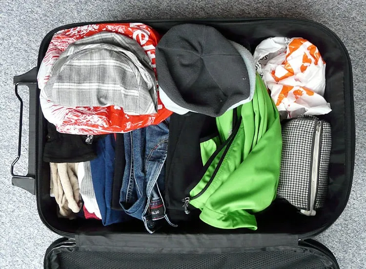 Unpacking an opened suitcase with clothes