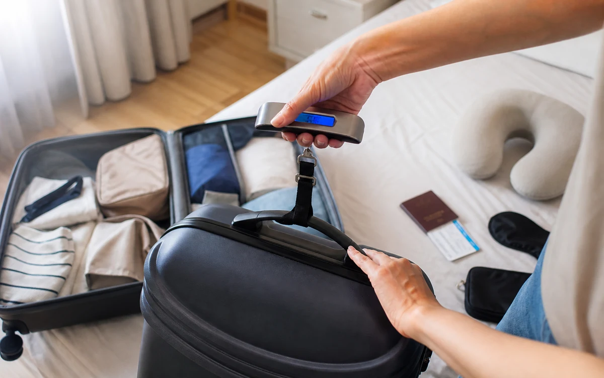Traveler weighing a checked suitcase before an international flight