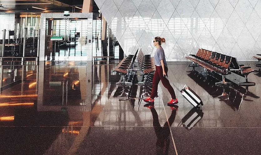 A woman with a suitcase walking inside an airport